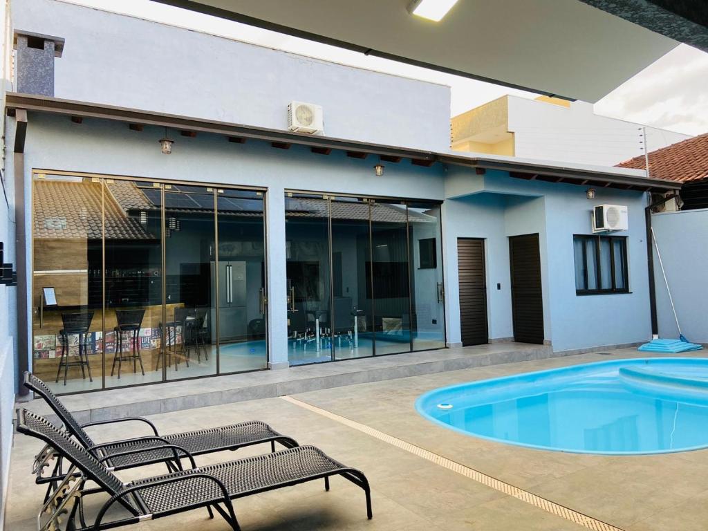 a patio with two chairs and a swimming pool at Casa Privativa na Av. Garibaldi Vila A in Foz do Iguaçu
