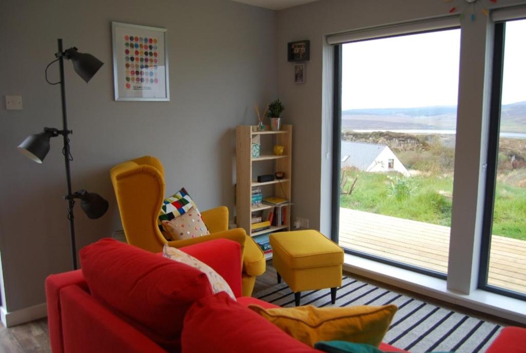 a living room with a red couch and yellow chairs at Wee Shed in Portree