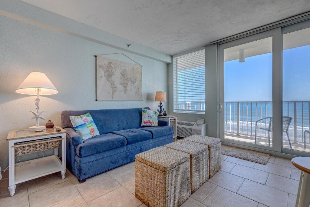 a living room with a blue couch and a balcony at The Ocean Calls, Unit #612 in Daytona Beach