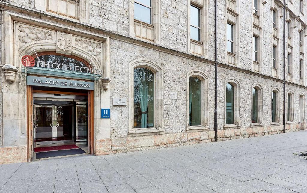 un grand bâtiment en pierre avec une entrée pour un magasin dans l'établissement NH Collection Palacio de Burgos, à Burgos