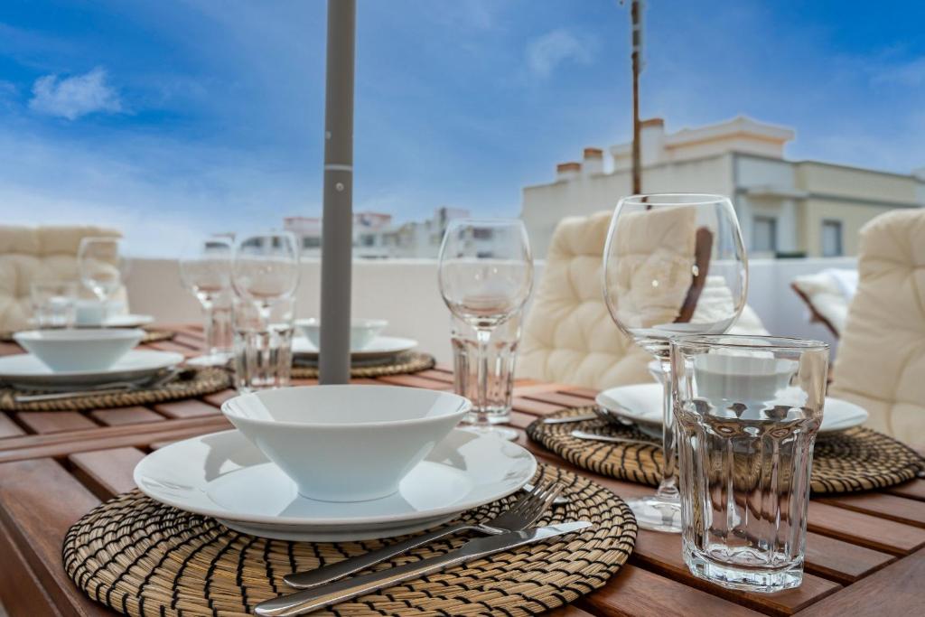 a wooden table with plates and glasses on it at Tia Anica House I - apartment with terrace in central Fuseta beach village in Fuzeta
