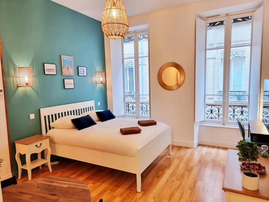 une chambre avec un grand lit blanc et deux fenêtres dans l'établissement The Republik - Studio Haussmannien près du panier, à Marseille