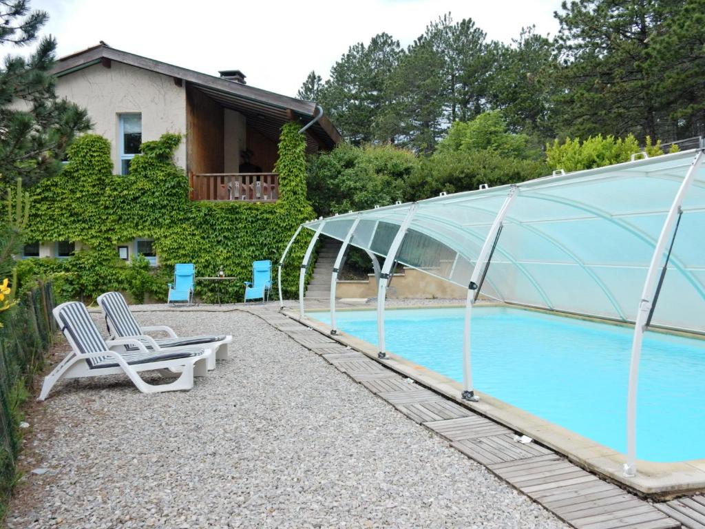 Ponet-et-Saint-AubanにあるHouse with private pool and beautiful viewのガラス張りの家とラウンジチェア付きのスイミングプール