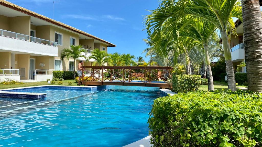 a swimming pool with a bridge in a resort at Village em Guarajuba in Guarajuba