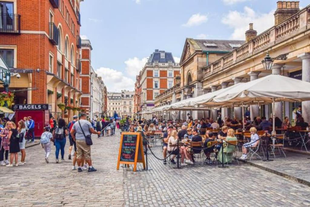 a crowd of people sitting at tables in a street at Covent Garden gem apartment in London