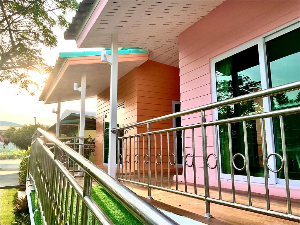 a pink house with a railing on a porch at Ban Ing Suan in Samutprakarn