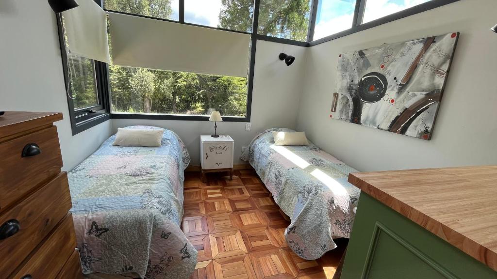duas camas num quarto com duas janelas em La Clarita em Villa La Angostura