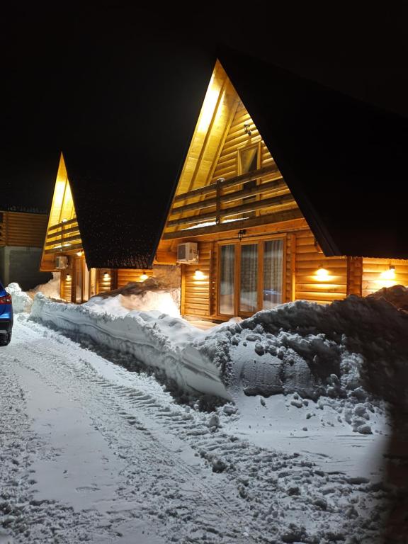 uma casa está coberta de neve à noite em Vrh Đevojka Villas em Žabljak