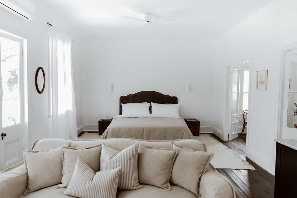 a white living room with a couch and a bed at The Postman's Cottage - Hinterland Luxury in Montville
