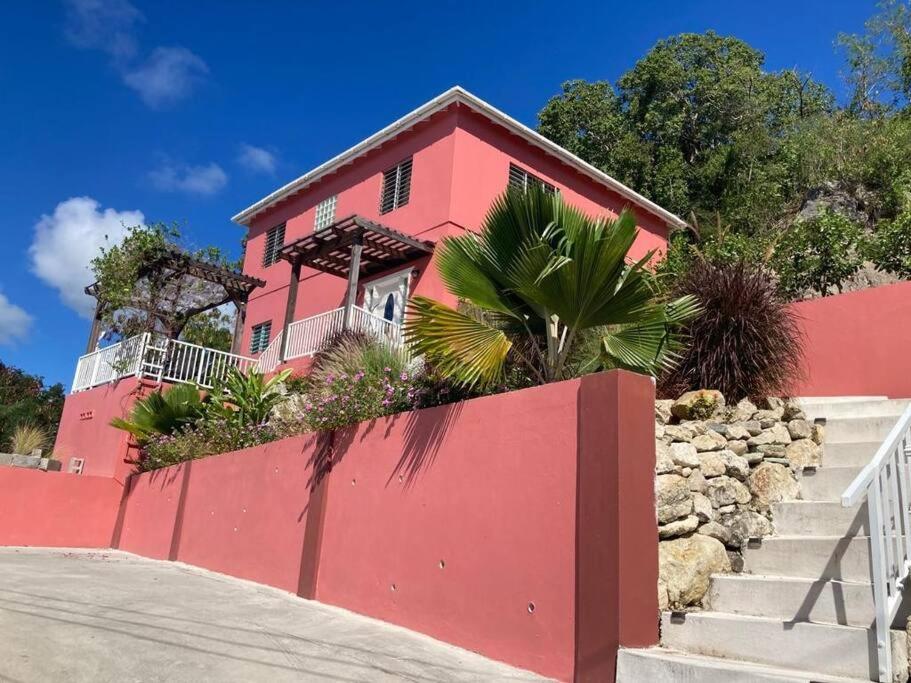 a pink house with a red wall and stairs at Mount Joy Getaway in Parham