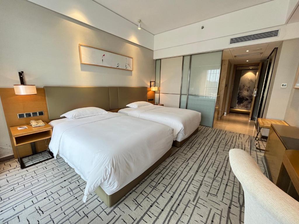 a large bedroom with two beds and a television at Guangzhou Nanhong Ausotel Hotel in Guangzhou