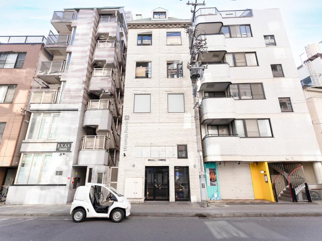 a small car parked in front of a tall building at Hiromas Hostel Yokohama Chinatown in Yokohama