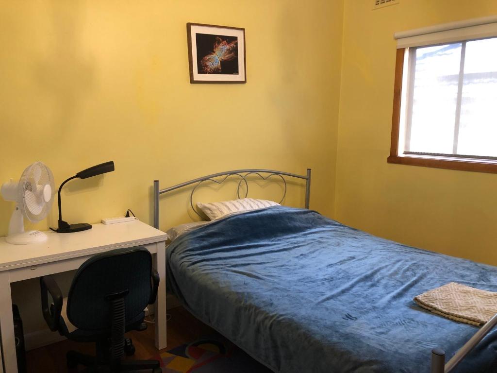 a bedroom with a bed and a desk with a lamp at A single room near the railway station in Melbourne