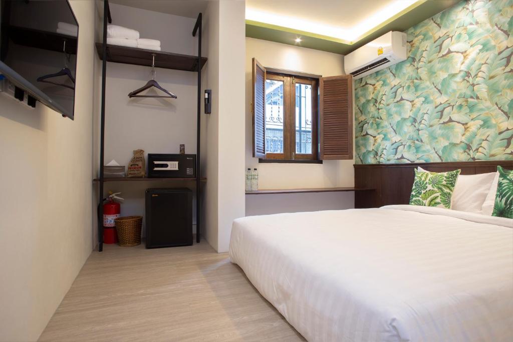 A bright guest room with a large bed, open storage, and a shuttered window.