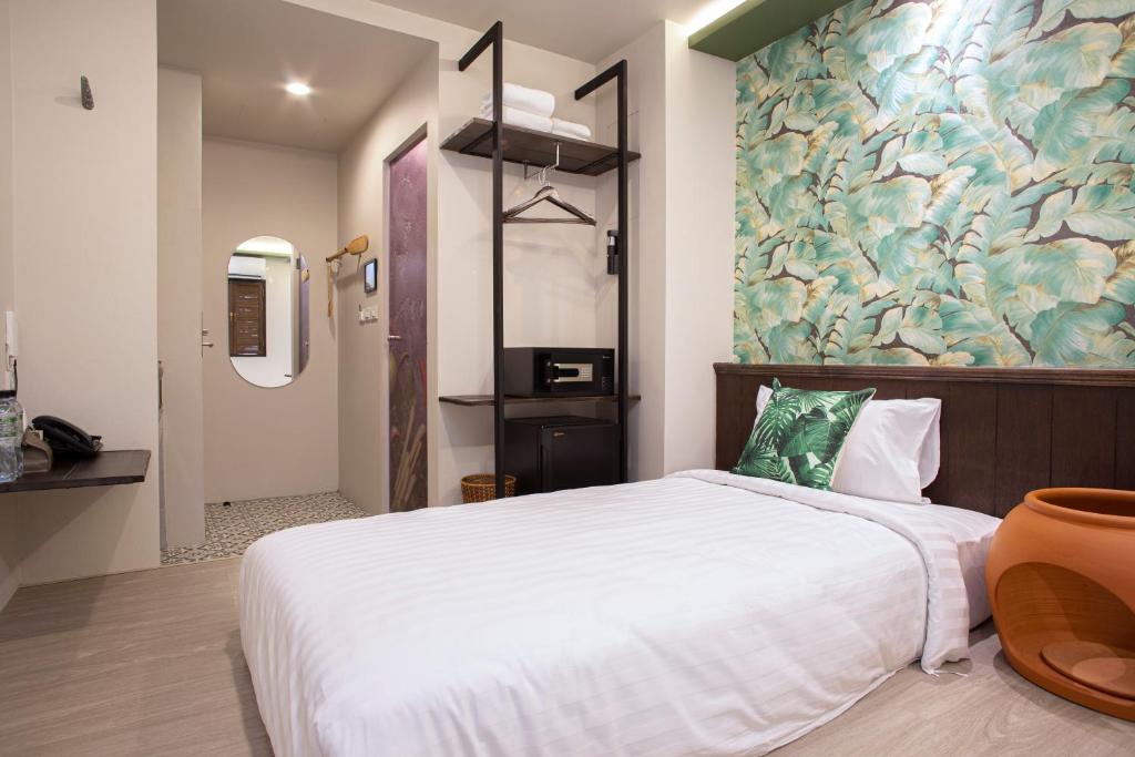 A compact double bedroom with a floral feature wall and open clothing storage.