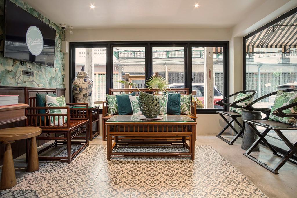 A bright lounge arranged around rattan seating, patterned flooring and street-facing windows.
