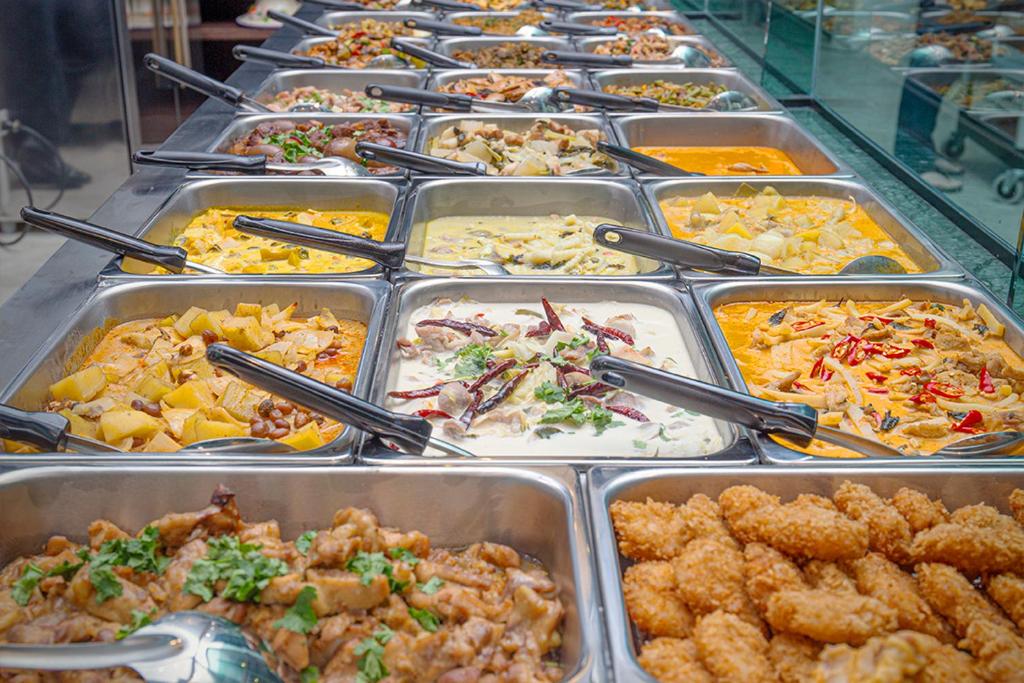 A close-up buffet line filled with trays of prepared hot and cold dishes.