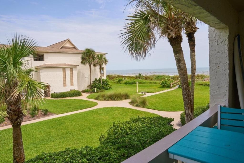 una casa con palmeras y un banco azul en un porche en Four Winds F8 condo, en St. Augustine