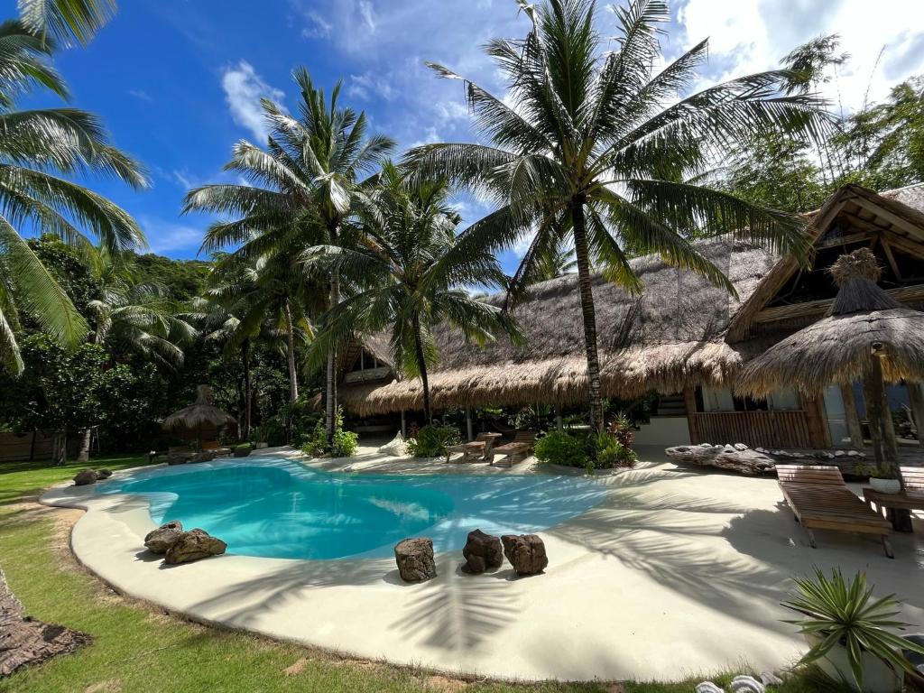 un complejo con una piscina con palmeras en The Beach House Ocam Ocam en Busuanga