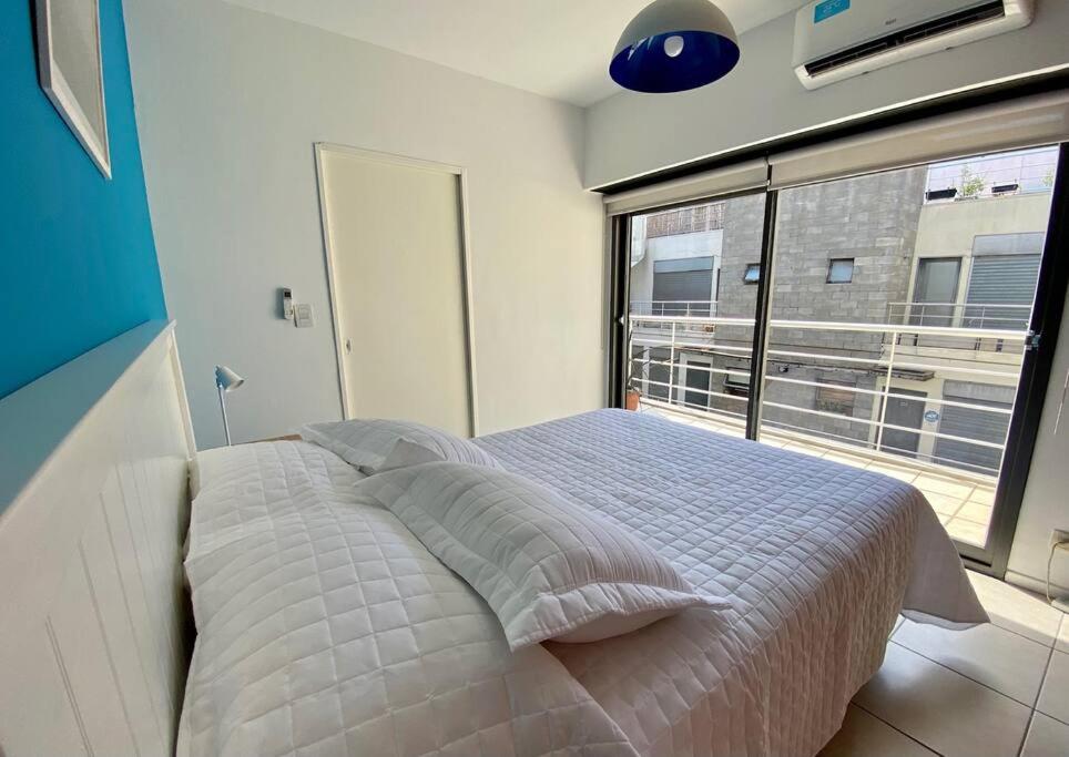 1 dormitorio con cama y ventana grande en Departamento con terraza, parrilla y piscina en Buenos Aires
