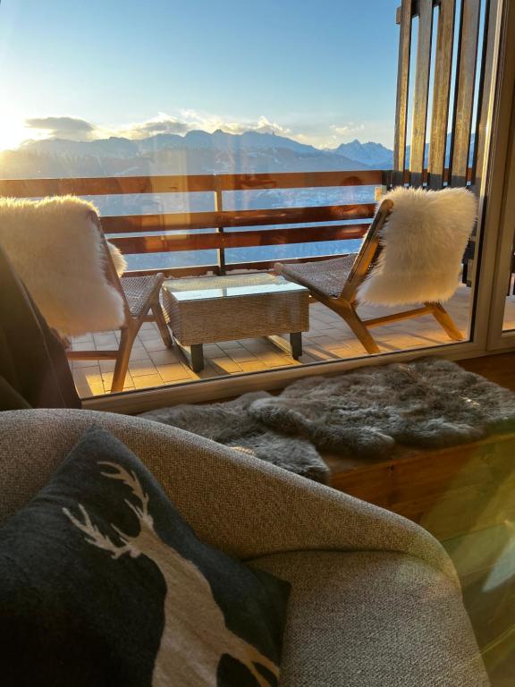 a living room with a couch and chairs on a balcony at Superbe studio Anzère, rénové, au pied des pistes in Anzère