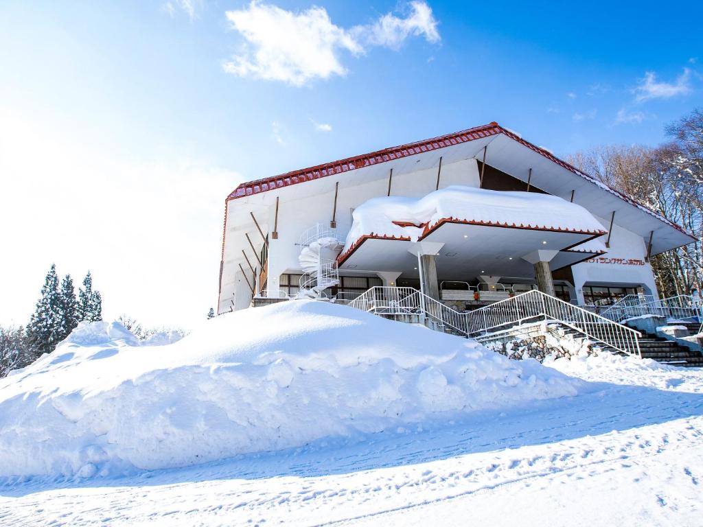 a building covered in snow next to a pile of snow at Kurohime Rising Sun Hotel in Shinano