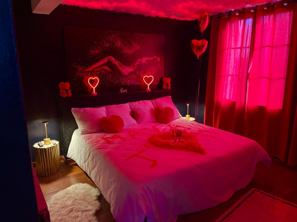 a bedroom with a pink bed with red lighting at Escapade jacuzzi in Caen