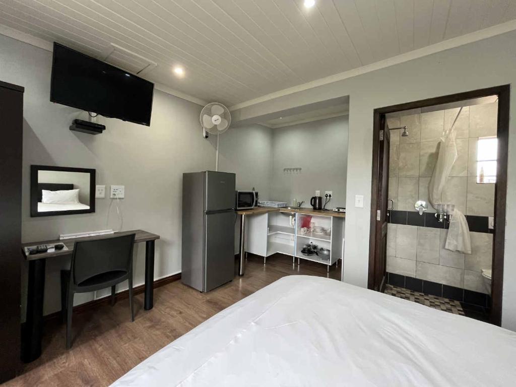 een slaapkamer met een bed, een bureau en een douche bij Halleria Self Catering in White River