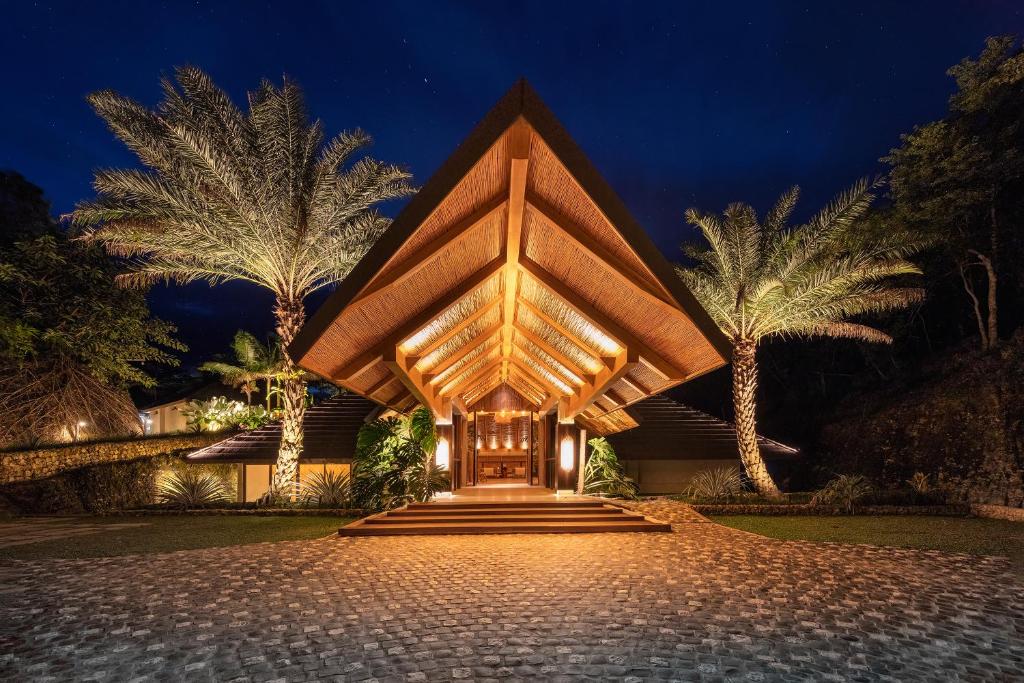 a building with a wooden structure with palm trees at Manami Resort 