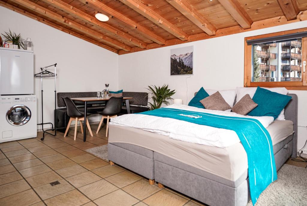 a bedroom with a bed and a table and a laundry machine at Solution-Grischun, Parkplatz - Küche- Wäschetrokner- Kaffee, Tee in Flims