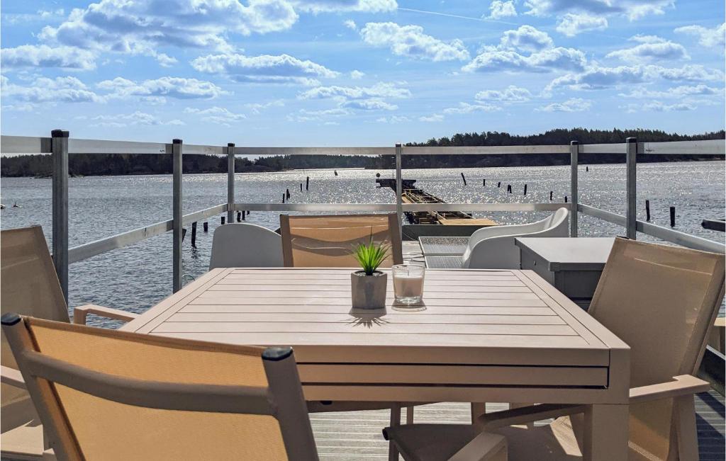 a wooden table and chairs on a deck with a beach at Stunning Ship-boat In Blankaholm With Wifi And 1 Bedrooms in Blankaholm