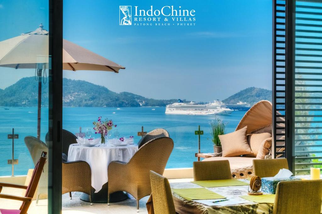 Indochine Resort and Villas - SHA Extra Plus في شاطيء باتونغ: مطعم مطل على المحيط وسفينة سياحية