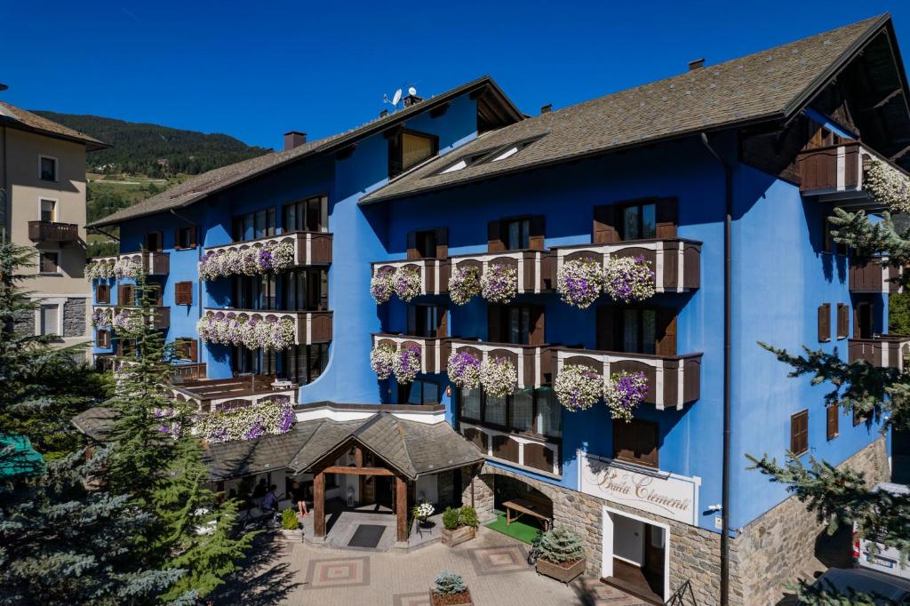 niebieski budynek z kwiatami na balkonach w obiekcie Hotel Baita Clementi w mieście Bormio