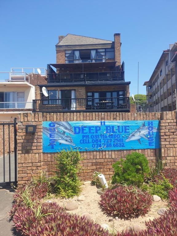 a sign on a brick wall in front of a house at Deep Blue Guest House in Amanzimtoti