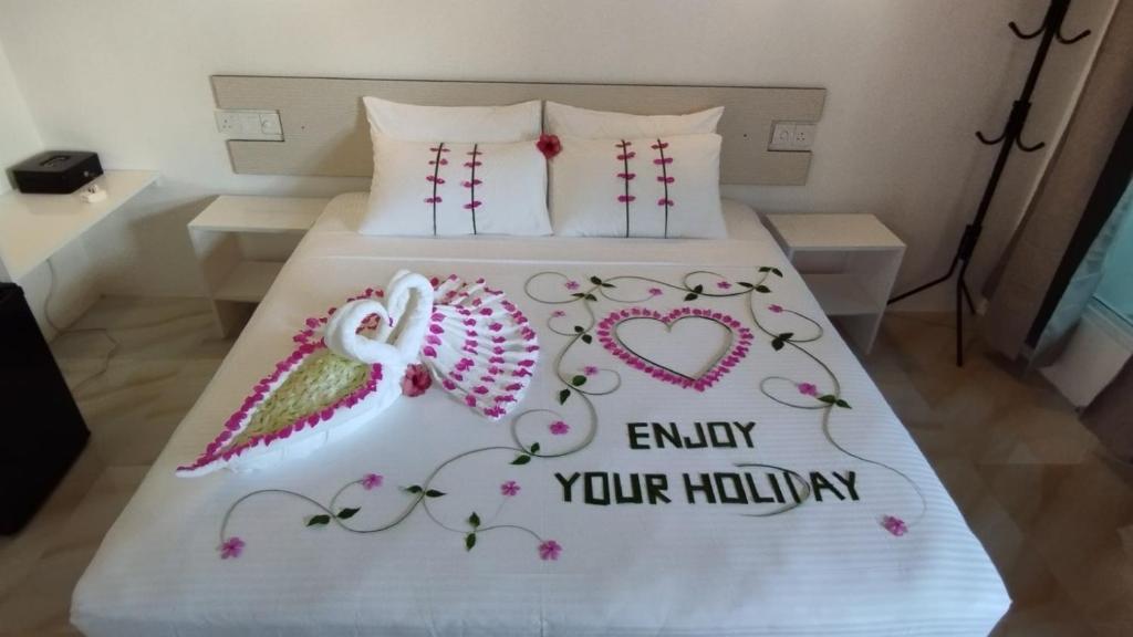 Un dormitorio con dos camas con corazones y las palabras disfrutar de su delirio en Thoddoo Garden inn en Thoddoo