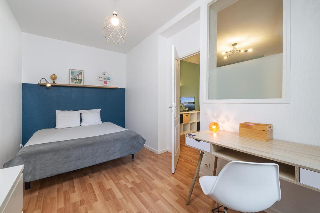 um quarto com uma cama, uma secretária e uma cadeira em Appart calme avec parking proche place Ney em Angers