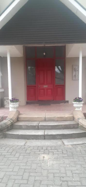 a red door of a building with stairs in front at The Terraces in Kroonstad