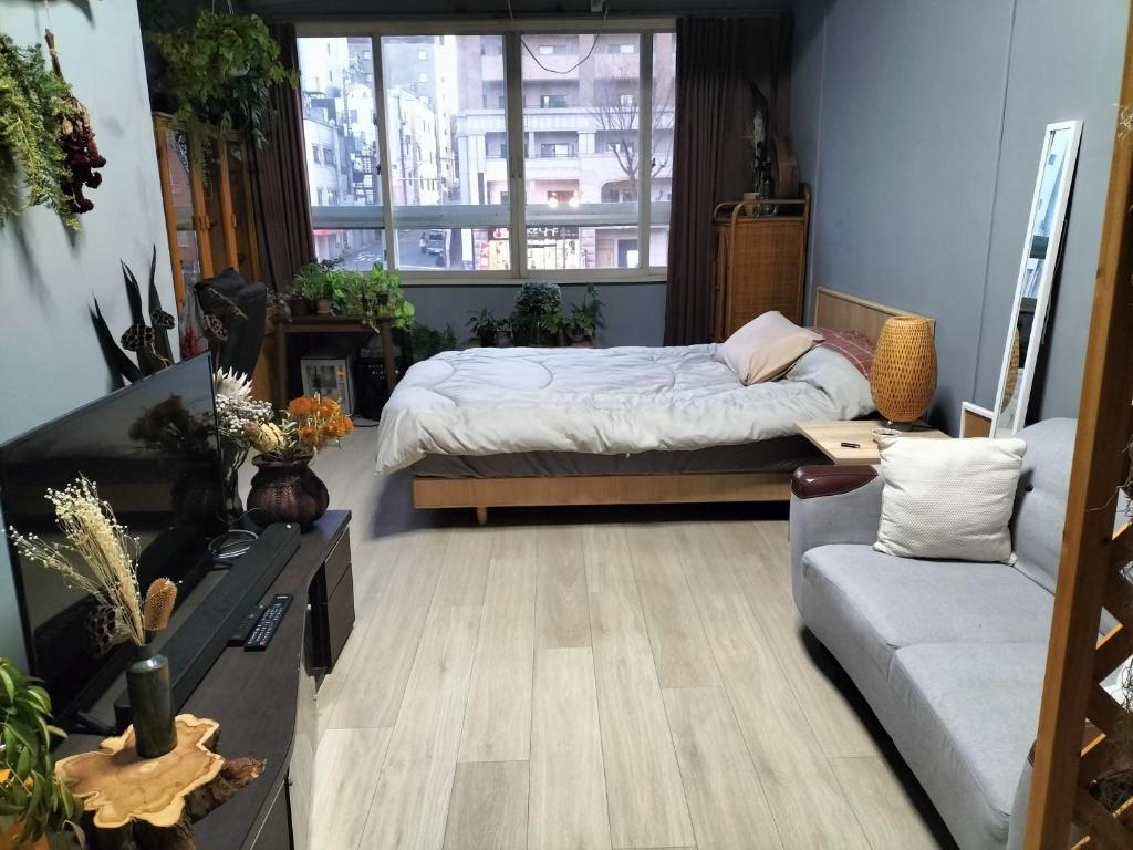 大阪的住宿－Backstage Party Hostel & Bar，一间卧室配有一张床和一张沙发