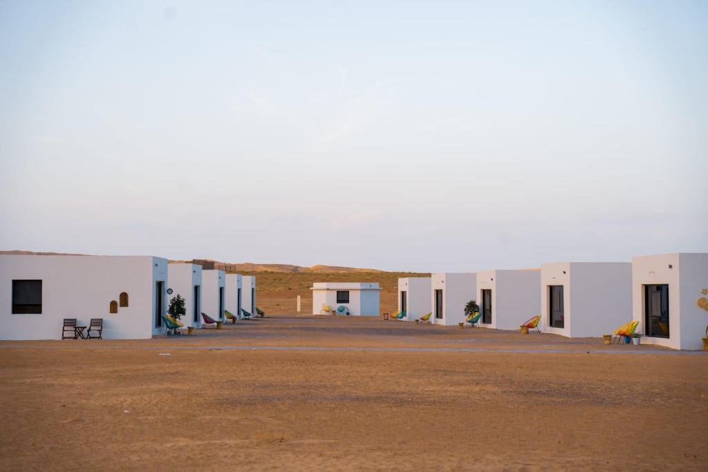 a row of white buildings in the desert at Safari Desert Camp in Shāhiq