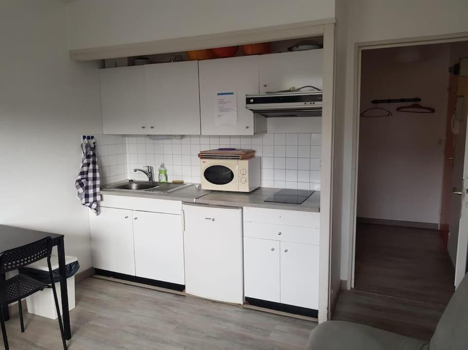 a kitchen with white cabinets and a sink and a microwave at Le studio 19 in Saint-Cast-le-Guildo