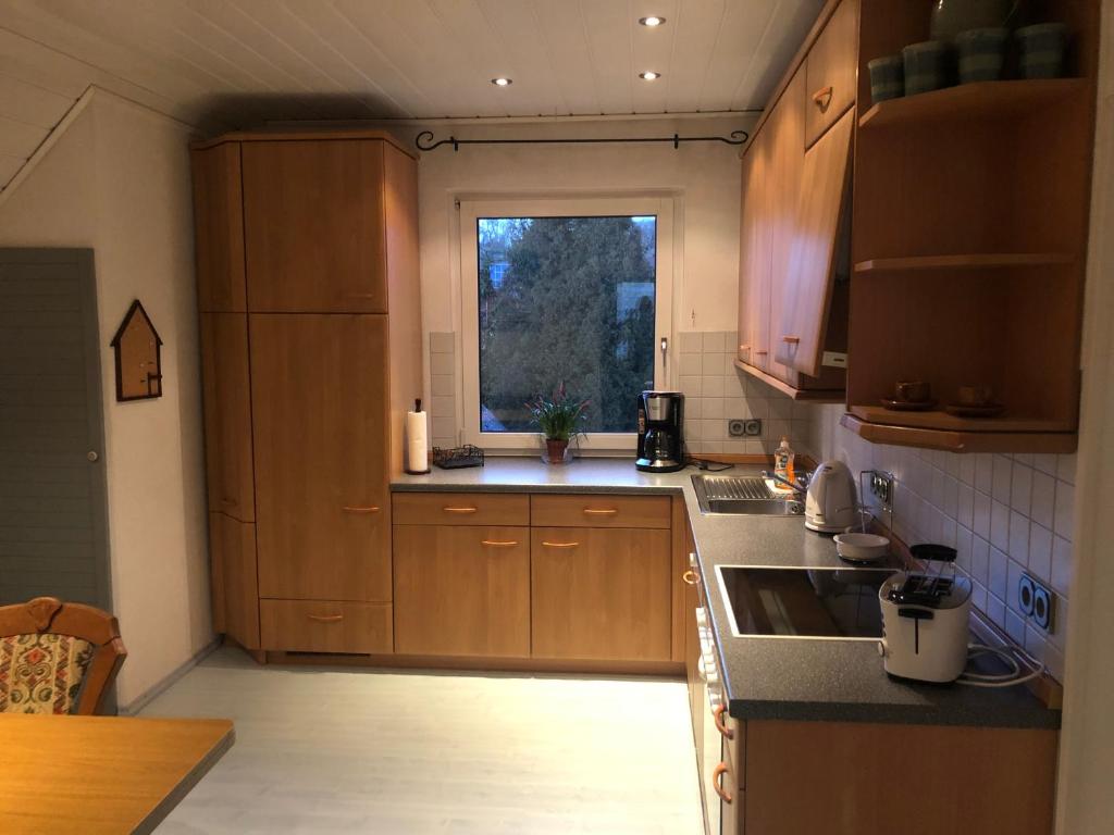 una pequeña cocina con armarios de madera y una ventana en Ferienwohnung Ober Widdersheim en Nidda
