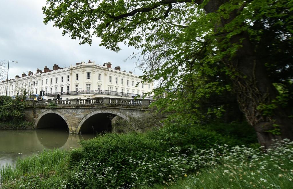 a bridge over a river with a white building at Terrace House in Leamington Spa