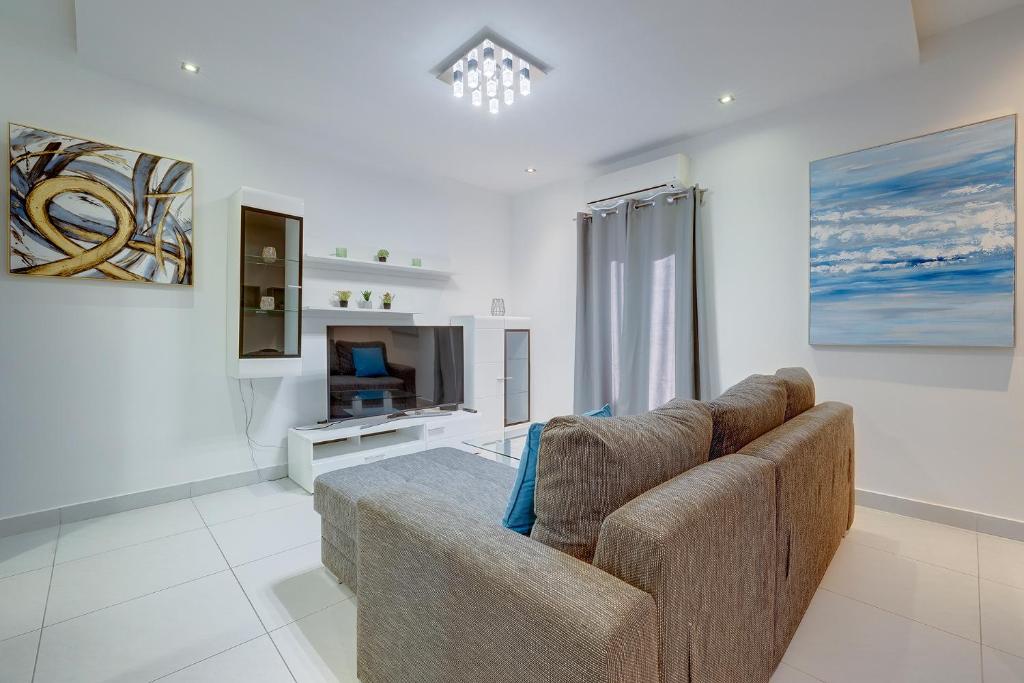 a living room with a couch and a television at Idyllic Apartment just off the Promenade in Sliema