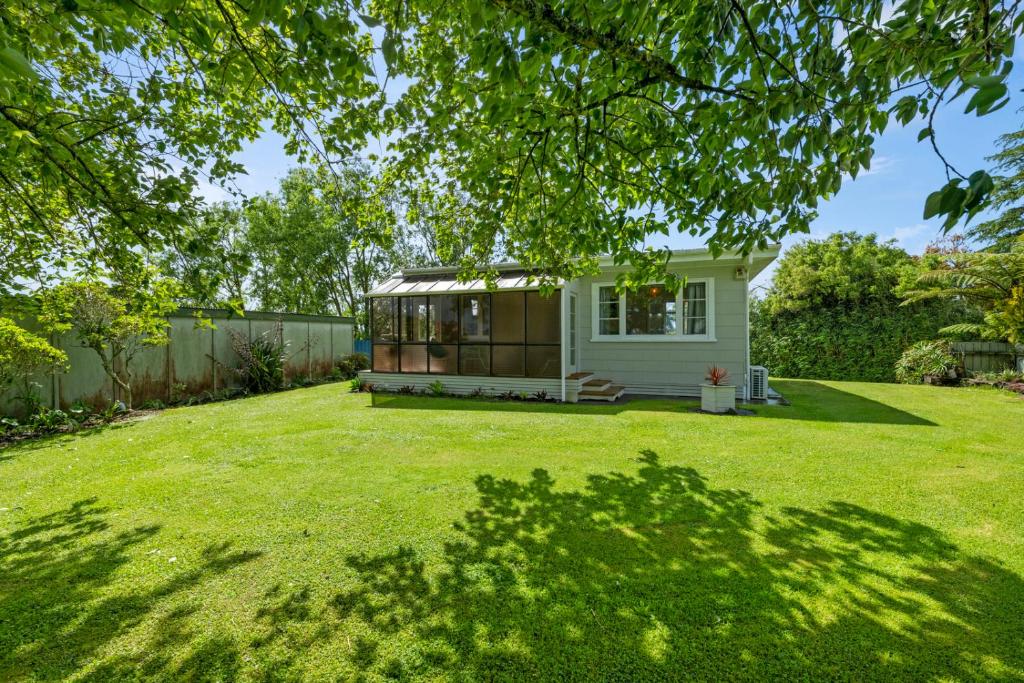 a small house in a yard with a green lawn at Carrington Countryside - New Plymouth Holiday Home in New Plymouth