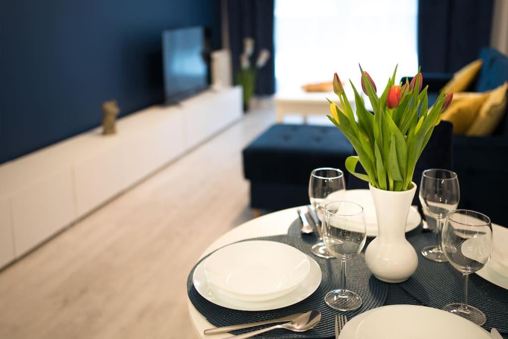 een tafel met borden en glazen en een vaas met bloemen bij Regal Park in Elblag