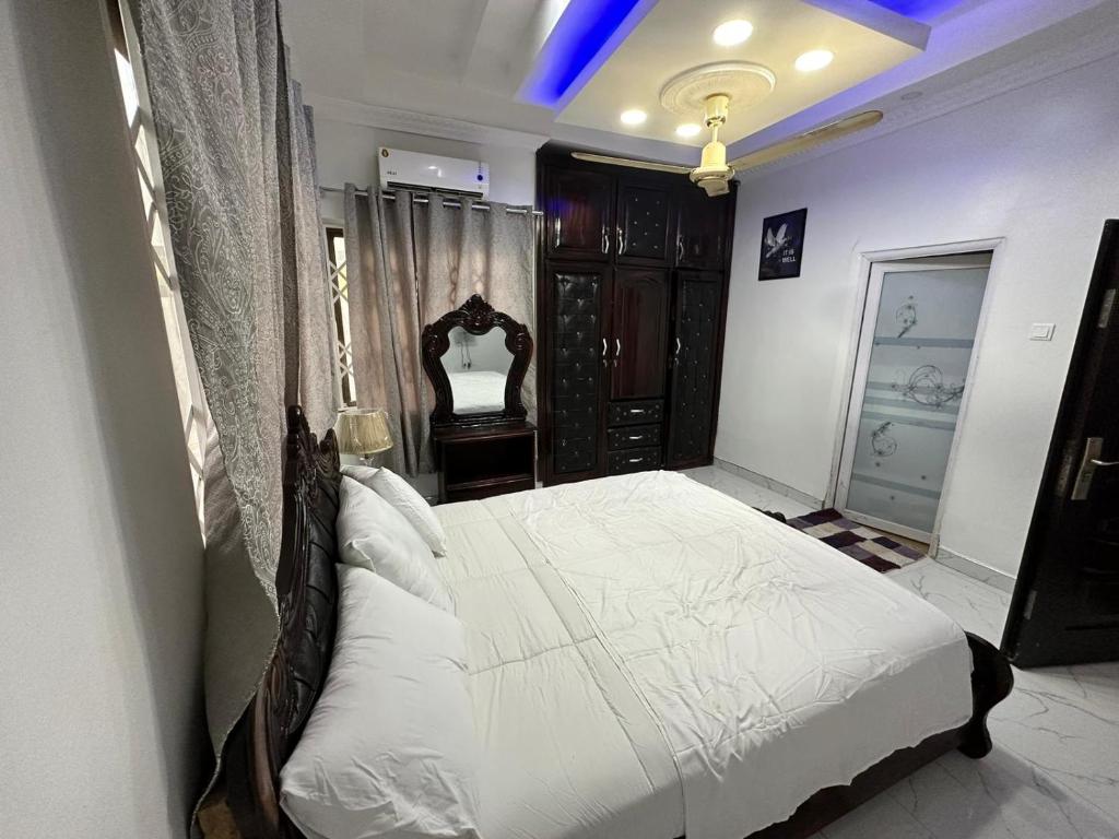 1 dormitorio con 1 cama grande con sábanas blancas en BENJI'S VILLA, en Kumasi
