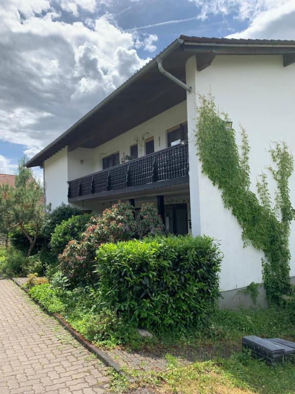 een wit huis met een balkon en struiken bij Gästezimmer - Mespelbrunn in Mespelbrunn