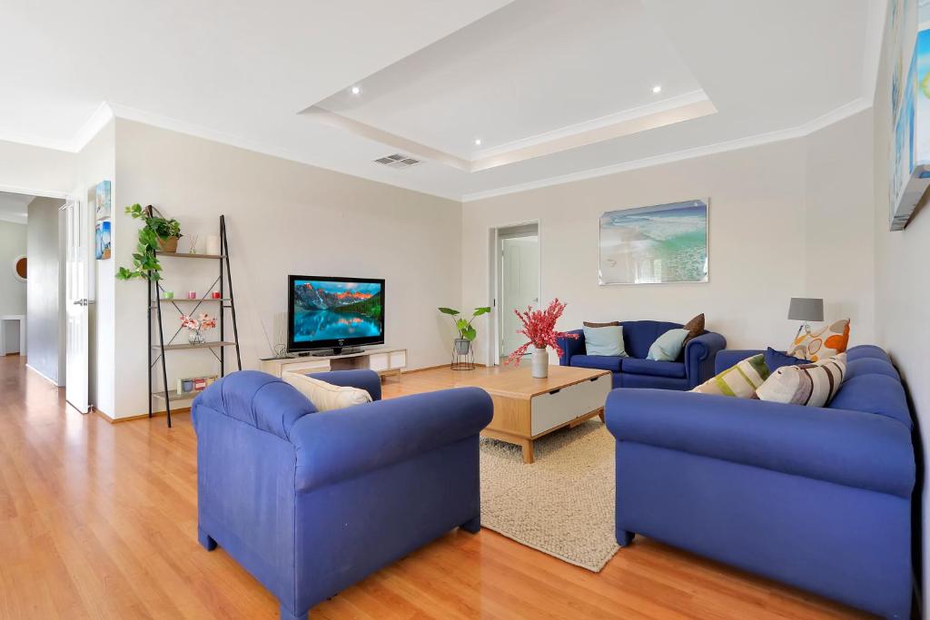 a living room with two blue couches and a tv at Daydream by the Sea! in Mandurah