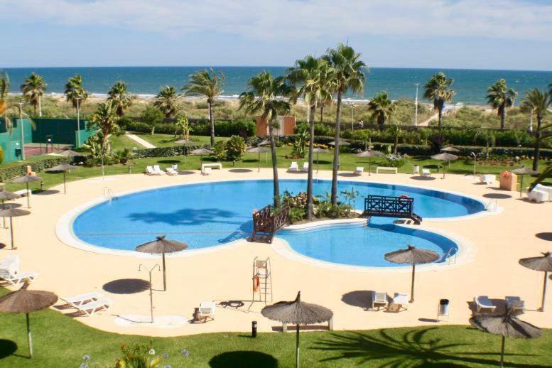 克莉絲蒂娜島的住宿－Islantilla Luxury，一个带遮阳伞和海滩的大型游泳池