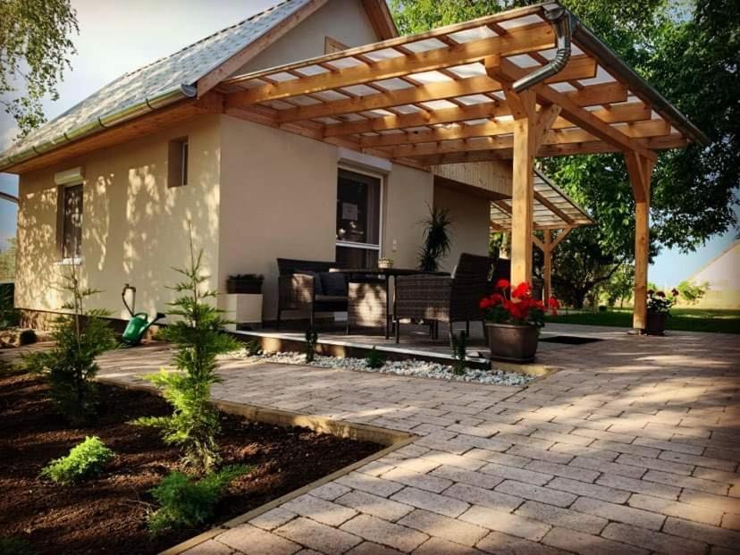 a patio with a wooden pergola in front of a house at Apróka Relax in Balatonlelle